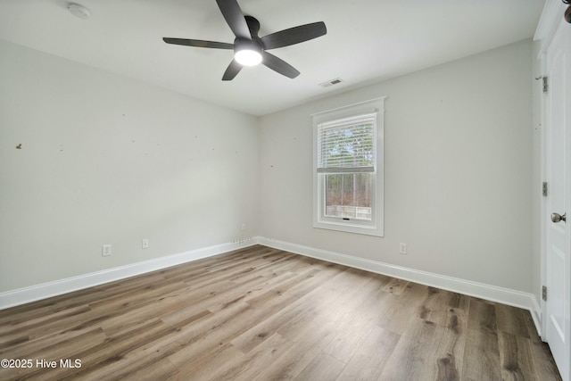 spare room featuring visible vents, wood finished floors, baseboards, and ceiling fan