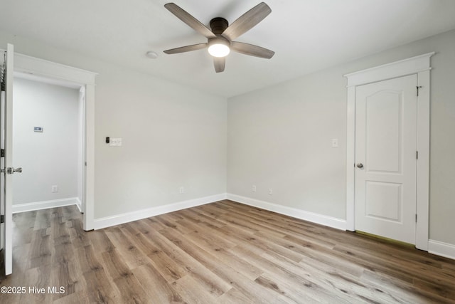 spare room featuring baseboards, wood finished floors, and a ceiling fan