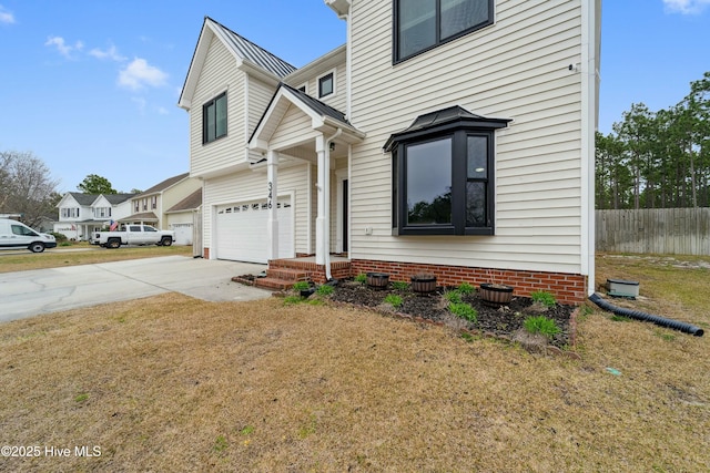 view of front of home with fence, a standing seam roof, an attached garage, concrete driveway, and metal roof