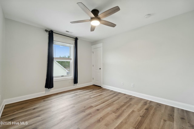 unfurnished room featuring light wood finished floors, visible vents, ceiling fan, and baseboards