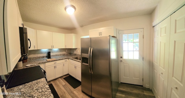3206 Deer Path Cir, New Bern, NC 28560 - kitchen featuring black appliances, a textured ceiling, wood finished floors, white cabinetry, and light stone countertops