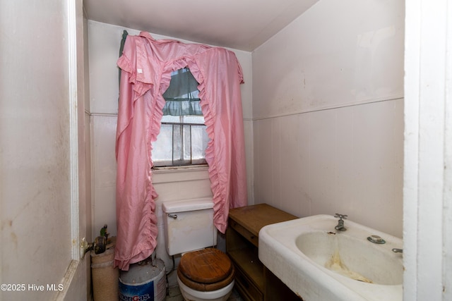 bathroom with a wainscoted wall and toilet