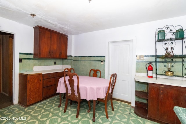 dining room with tile patterned floors, wainscoting, and tile walls