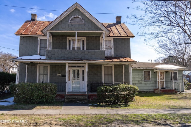 view of front of home featuring a balcony, covered porch, and a chimney