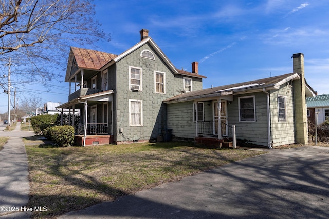 view of front of home featuring a balcony and a chimney