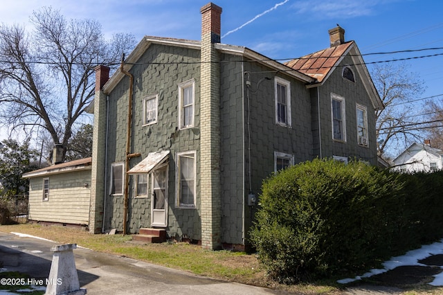 view of side of property with entry steps and a chimney