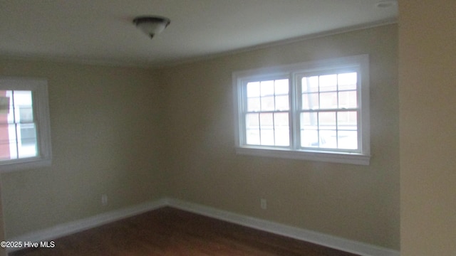 spare room with baseboards and dark wood-style flooring