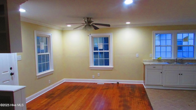 kitchen featuring a sink, baseboards, ornamental molding, and a ceiling fan