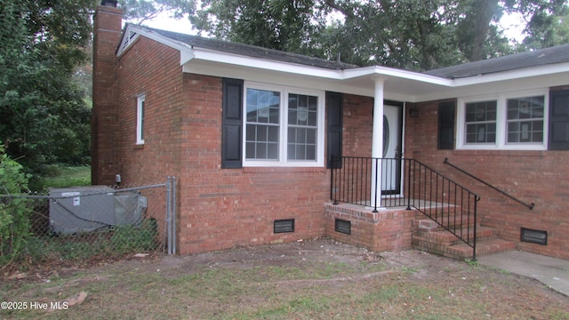 view of front facade with brick siding, a chimney, and fence