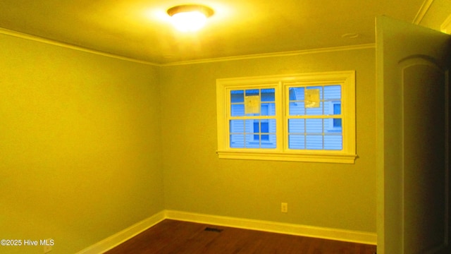 unfurnished room featuring baseboards, dark wood finished floors, and crown molding