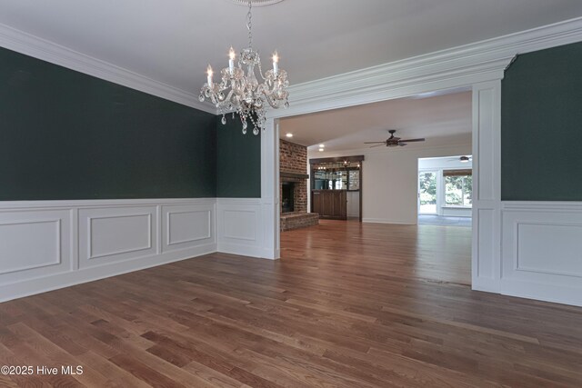 240 Donald Ross Dr, Pinehurst, NC 28374 - unfurnished dining area with crown molding, a fireplace, a decorative wall, a chandelier, and dark wood-style flooring