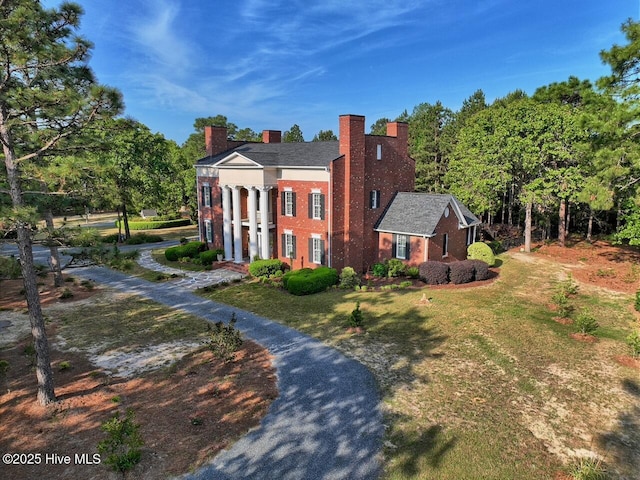 6680 Beulah Hill Church Rd, West End, NC 27376 - neoclassical home featuring a chimney, a front yard, and view of wooded area