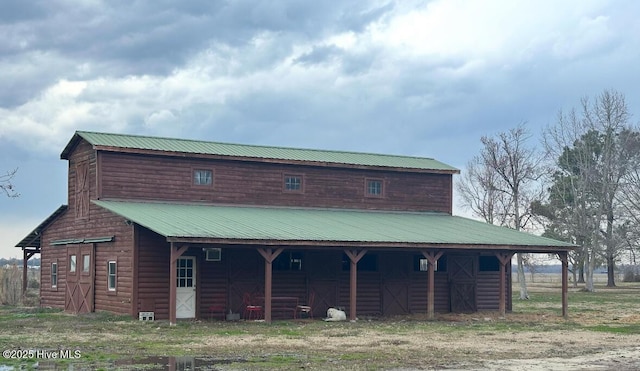 rear view of house featuring log veneer siding, metal roof, an exterior structure, and an outdoor structure