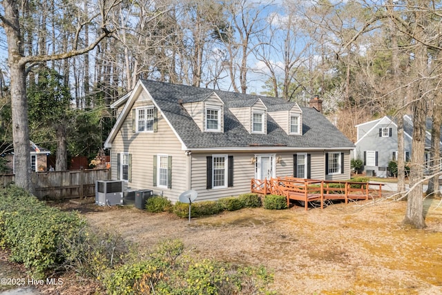 back of house featuring cooling unit, a deck, a chimney, and fence