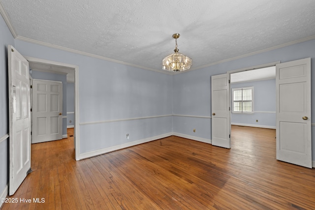 spare room with baseboards, a chandelier, ornamental molding, hardwood / wood-style floors, and a textured ceiling