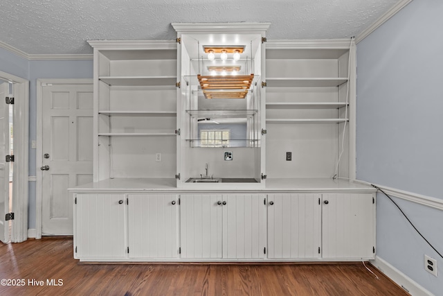 interior space with open shelves, a textured ceiling, dark wood-style floors, and crown molding