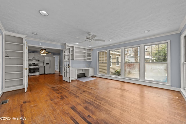 unfurnished living room featuring a ceiling fan, visible vents, dark wood-type flooring, a textured ceiling, and crown molding