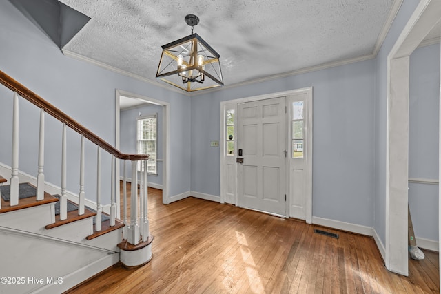 entryway with light wood-style flooring, crown molding, stairs, and baseboards