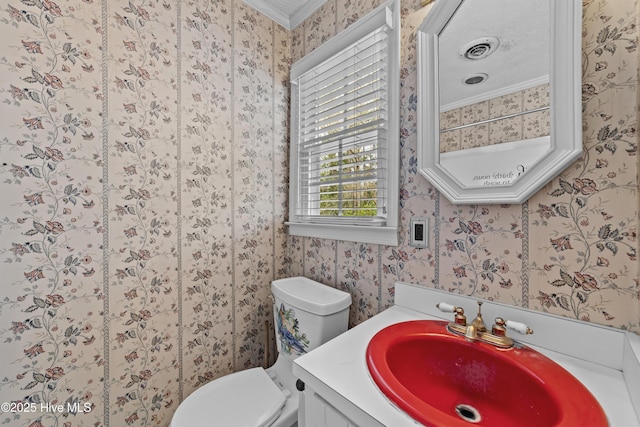 bathroom with toilet, ornamental molding, a textured ceiling, wallpapered walls, and vanity