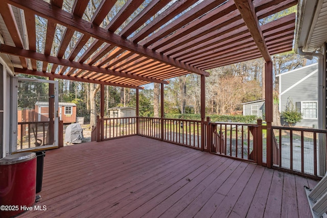 wooden deck featuring a storage shed, an outbuilding, and a pergola