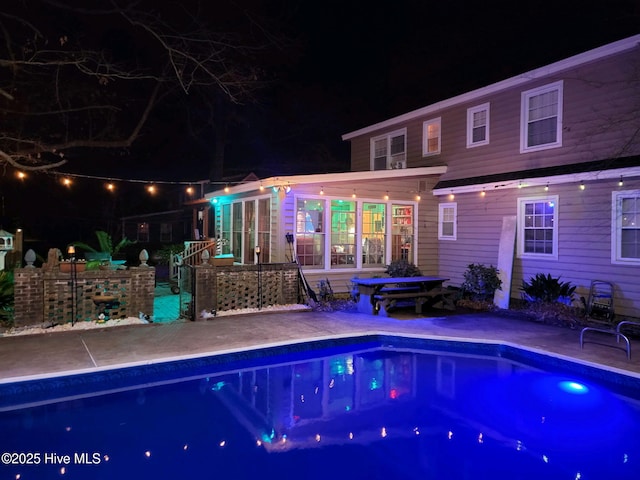 pool at twilight with a patio area and an outdoor pool