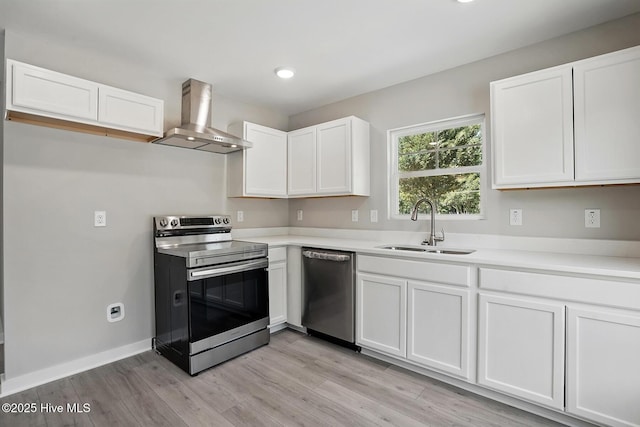 kitchen featuring stainless steel appliances, wall chimney range hood, a sink, white cabinetry, and recessed lighting