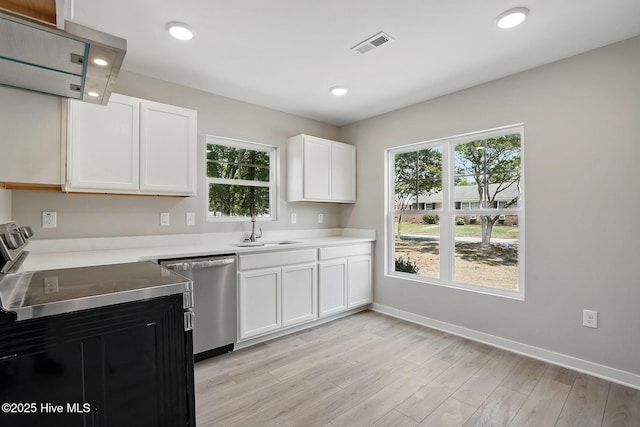 kitchen featuring stainless steel dishwasher, a sink, light countertops, light wood-style floors, and white cabinetry