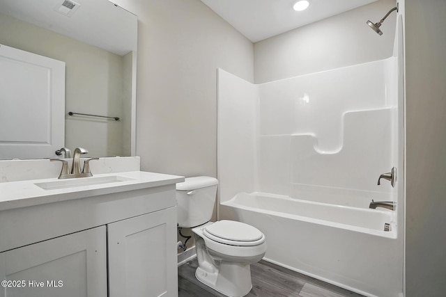 bathroom with toilet, wood finished floors, vanity, and shower / bathtub combination