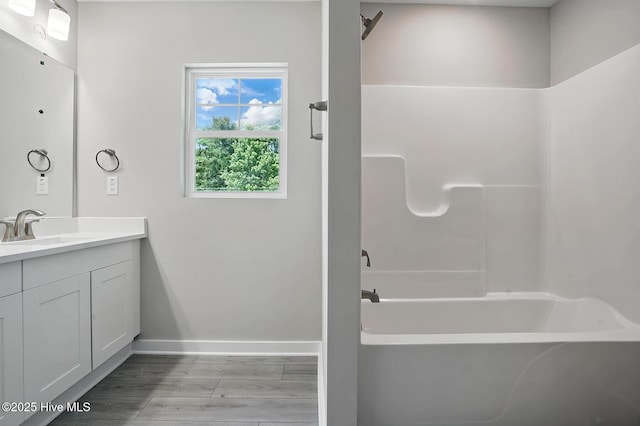full bathroom featuring baseboards, vanity, wood finished floors, and washtub / shower combination