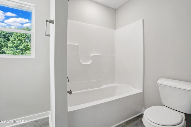 bathroom with baseboards, toilet, wood finished floors, and bathing tub / shower combination