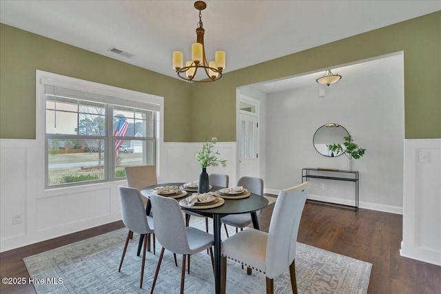 dining room featuring a wainscoted wall, visible vents, dark wood-type flooring, a decorative wall, and a chandelier