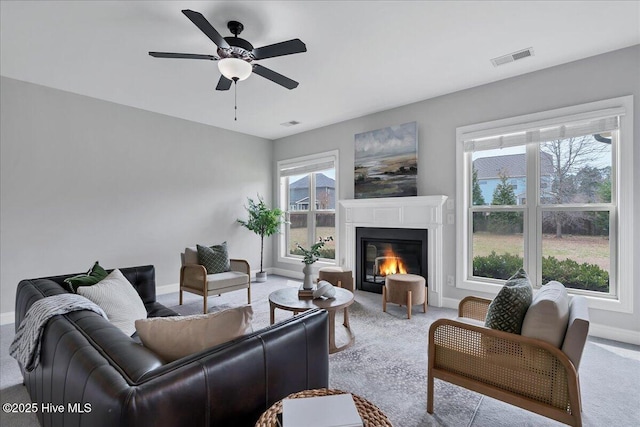 living area with visible vents, plenty of natural light, baseboards, and carpet