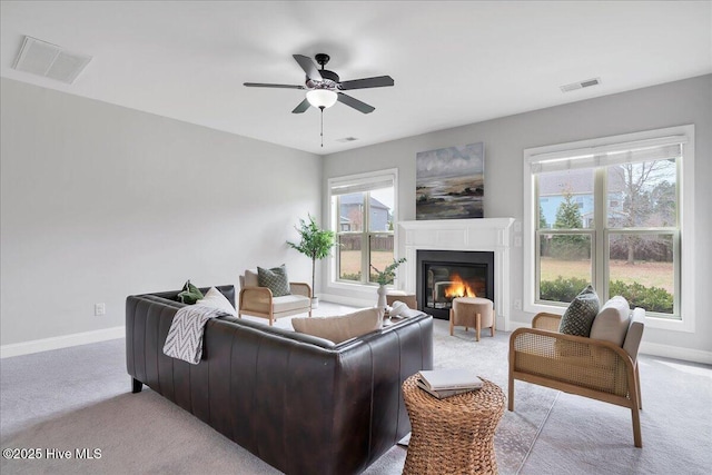 living room with a wealth of natural light, visible vents, light colored carpet, and a ceiling fan