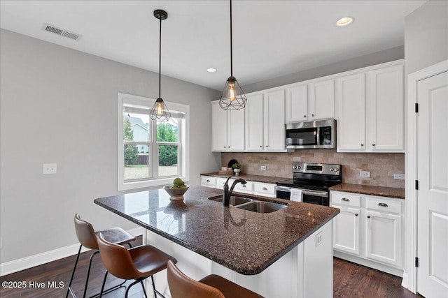 kitchen with tasteful backsplash, visible vents, white cabinets, stainless steel appliances, and a sink