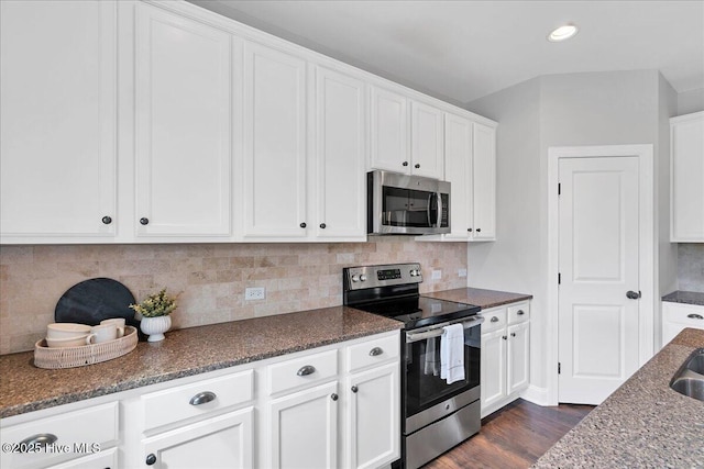 kitchen with white cabinetry, dark stone countertops, backsplash, and stainless steel appliances