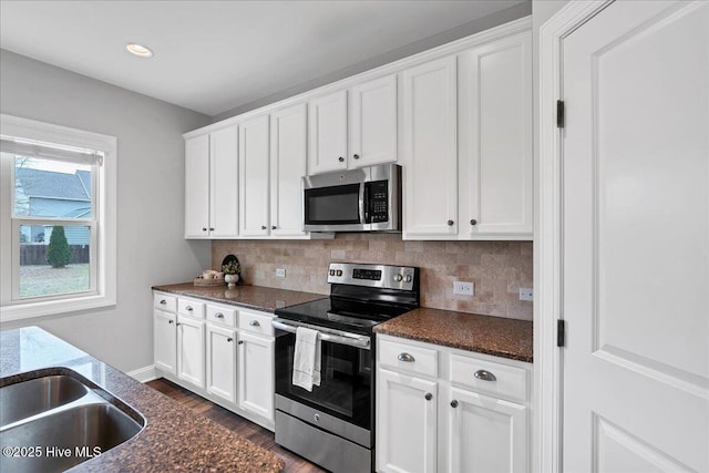 kitchen with dark wood finished floors, white cabinets, tasteful backsplash, and stainless steel appliances