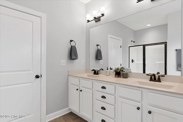 bathroom featuring a sink, double vanity, a shower stall, and tile patterned floors