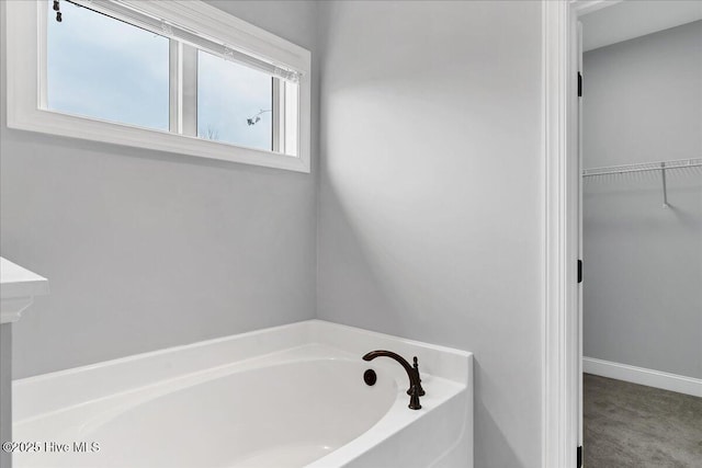 full bathroom with a spacious closet and a bath