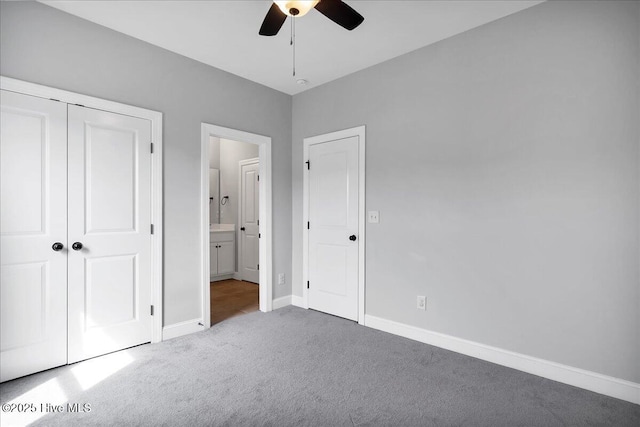 unfurnished bedroom featuring ensuite bathroom, a closet, carpet flooring, baseboards, and ceiling fan