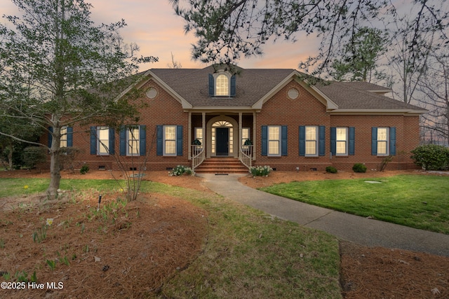 view of front of house with crawl space, a yard, a shingled roof, and brick siding