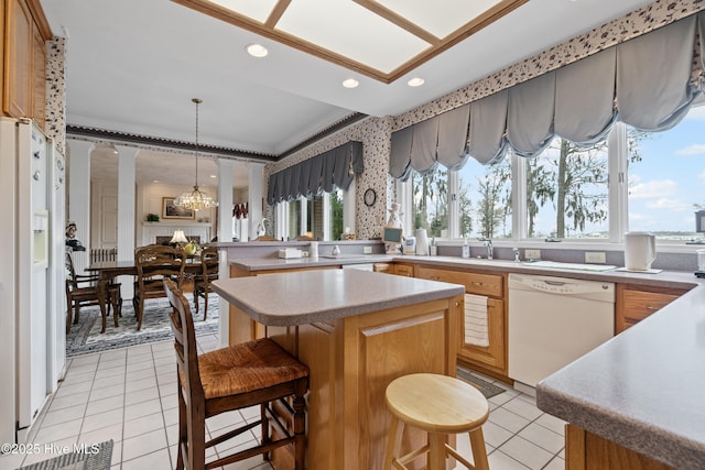 kitchen with light tile patterned flooring, white appliances, light countertops, and ornate columns