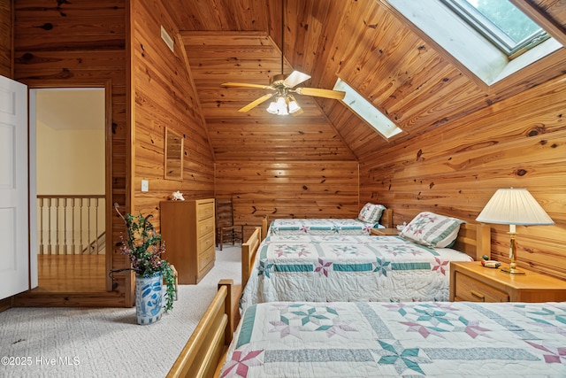 bedroom with wood ceiling, vaulted ceiling with skylight, carpet floors, and wood walls