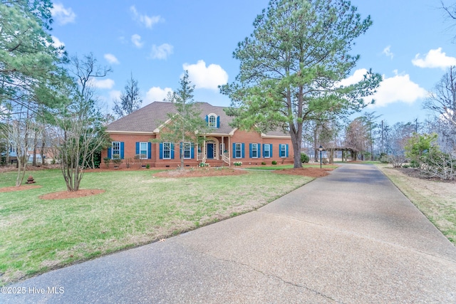 view of front facade featuring a front yard, roof with shingles, and driveway