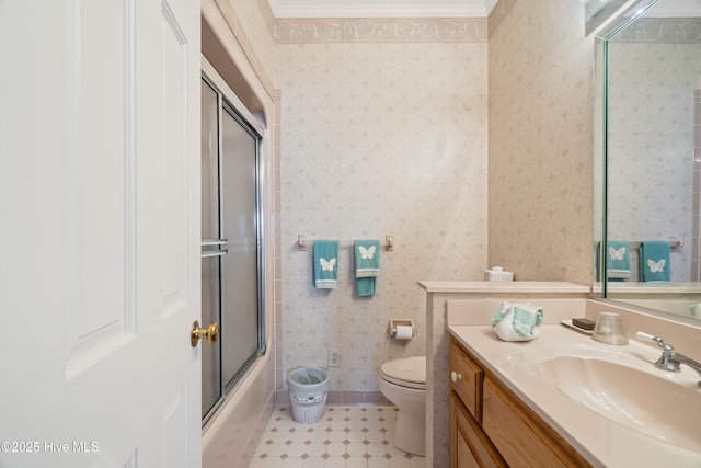 bathroom featuring tile patterned flooring, wallpapered walls, bath / shower combo with glass door, toilet, and vanity