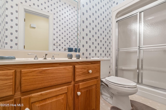 bathroom with wallpapered walls, toilet, vanity, and a stall shower