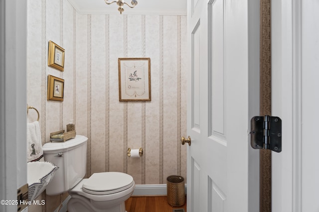 half bath featuring baseboards, toilet, wood finished floors, and wallpapered walls