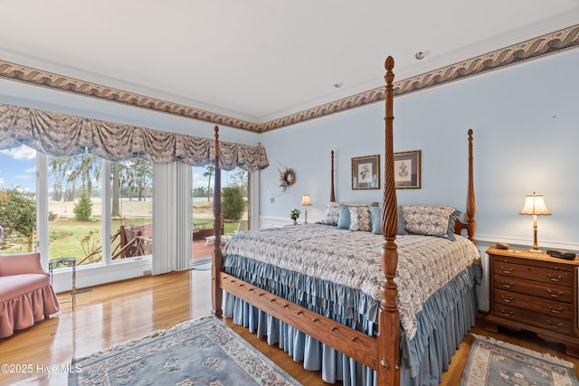bedroom featuring access to exterior, wainscoting, and wood finished floors