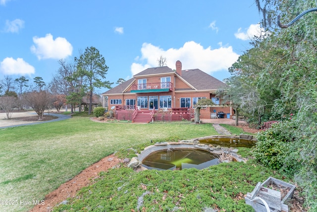 rear view of house featuring brick siding, a garden pond, a lawn, and a chimney