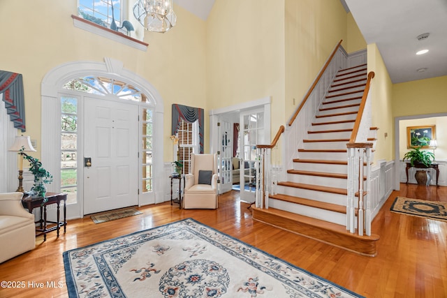 foyer featuring stairway, a high ceiling, an inviting chandelier, and hardwood / wood-style flooring