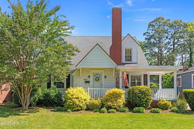 view of front of house with covered porch, a chimney, and a front yard